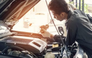 Car mechanic in grey uniform are checking the level of the engine oil, Automotive industry and garage concepts.